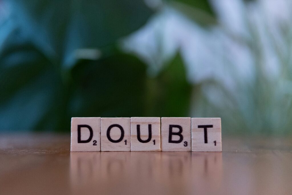 Close-up of Scrabble tiles spelling 'doubt' on a wooden surface, conveying uncertainty.