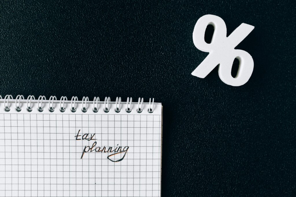 A notebook with 'tax planning' written on a grid paper next to a percent symbol on a black background.