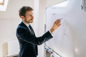 Home Executive in suit writing on whiteboard, explaining business graph.